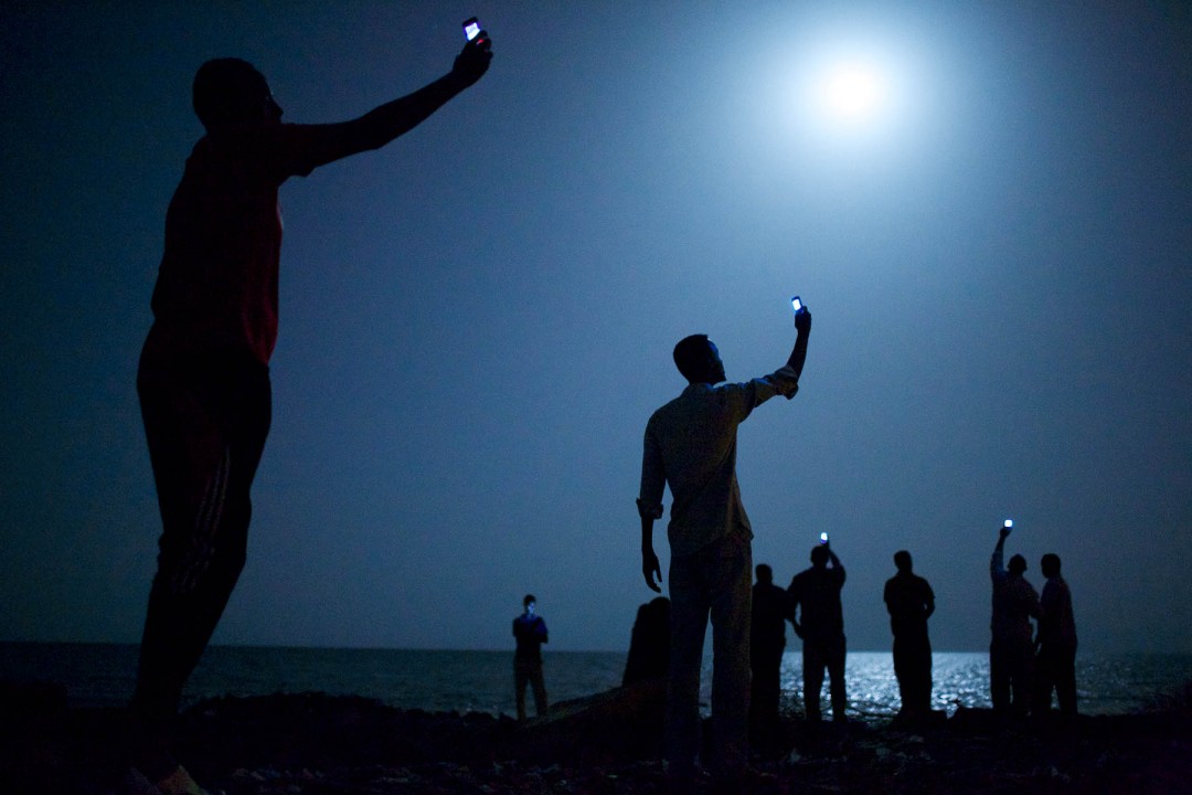 I место в категории «Современные проблемы», Джон Стенмайер (John Stanmeyer, США) «Сигнал». Африканские мигранты на берегу Аденского залива возле Джибути (Восточная Африка). В ночное время они пытаются поймать сигнал недорогой мобильной связи из соседнего государства Сомали, чтобы связаться со своими родственниками.